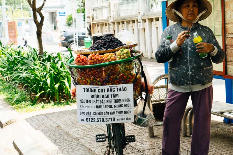 A woman with a basket full filled with fruits for sale and Saigon Vietnam