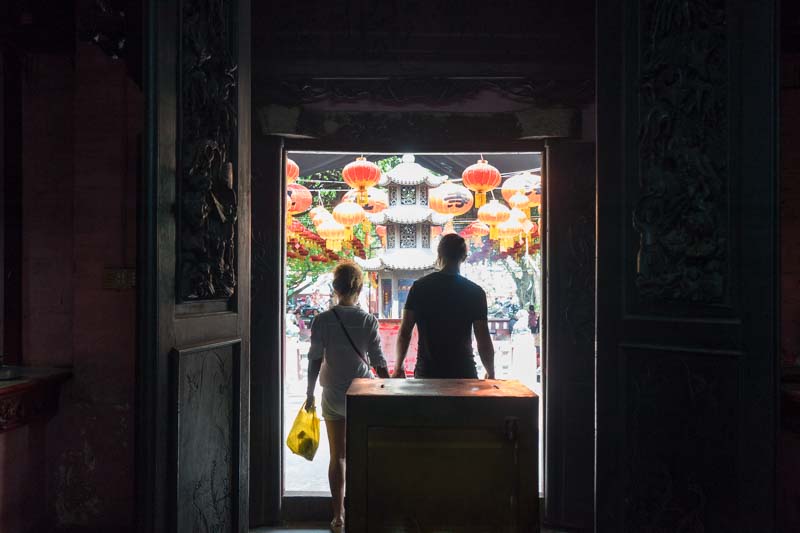 Two people leaving the temple entering a courtyard filled with lanterns in Saigon Vietnam