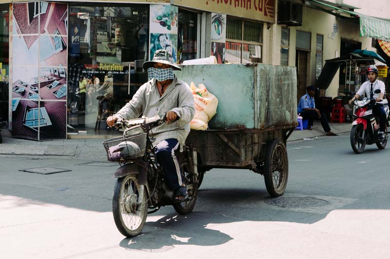 A photograph of a merchant on his motorcycle with a trailer in Saigon Vietnam