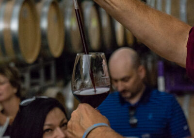 A wine maker, using a thief to put wine into a wine glass at Experience Alexander Valley